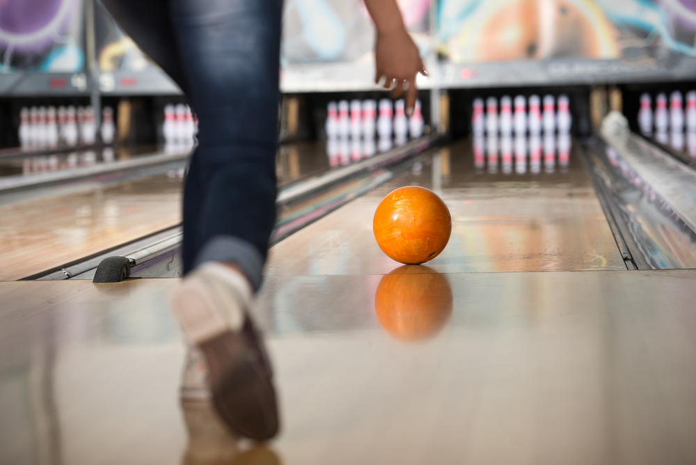 Female athlete bowling with yellow ball