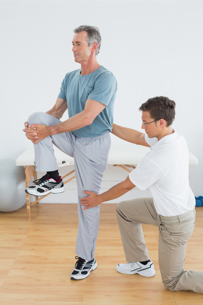 Male physical therapist helping patient with balance