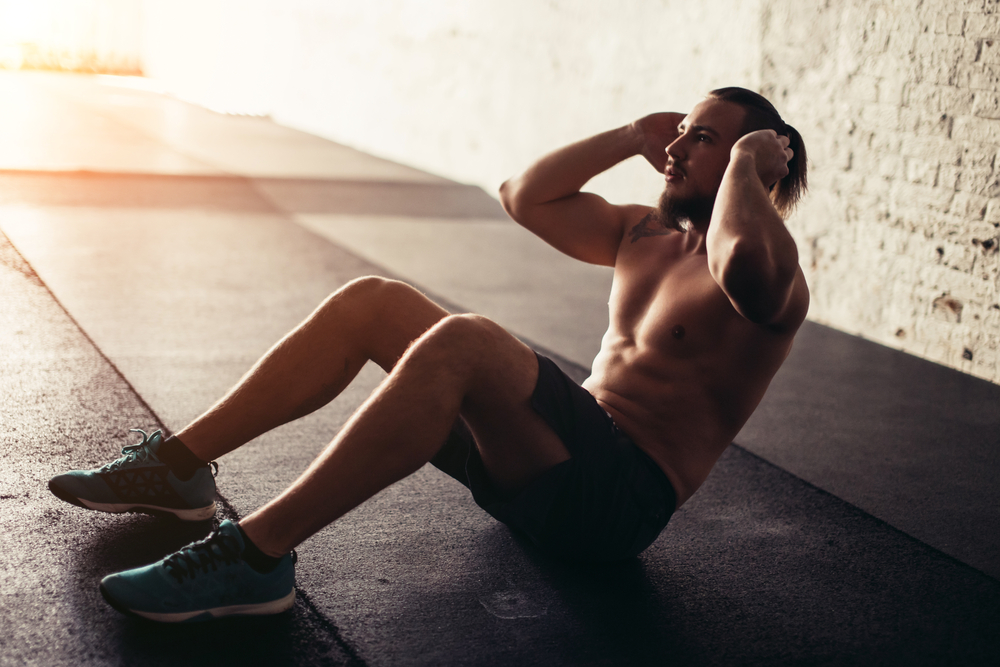 Muscular man exercising doing sit up exercise. Athlete with six pack, white male, no shirt