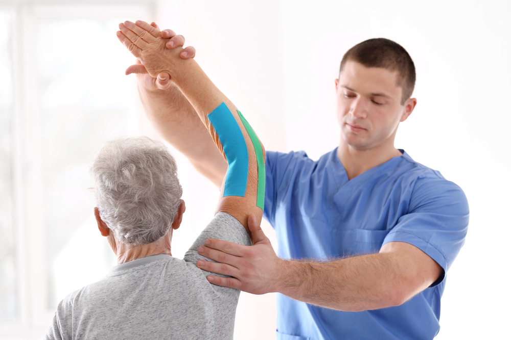 Physical therapist working with elderly woman to treat elbow injury